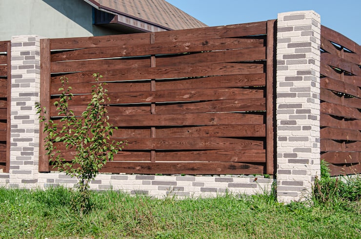 decorative-concrete-fence-with-brick-posts-near-residential-building-with-garden_140282-358